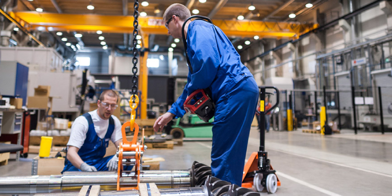 The Image Featuring Two People Analysing A Machinery In An Industrial Unit